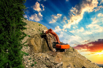 Wall Mural - Excavator at a construction site on the side of a hill against a cloudy blue sky. Compact construction equipment for earthmoving works. An indispensable assistant in excavation works.