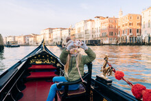 A Girl Captures Her Venetian Gondola Experience With A Toy Camera, Historic Buildings Line The Grand Canal In The Golden Hour