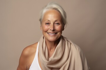 Wall Mural - Smiling senior woman with a beige scarf on a beige background