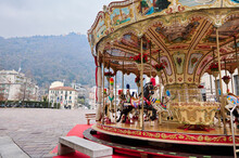 A Merry Go Round, Victorian Carousel At Christmas Fairground In Como, Against Italian Alps Backdrop On Cloudy Winter Day