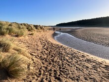 Beautiful Landscape Of Beach At Holkham With Pool Of Sea Salt Water Between Grassy Sand Banks On Cold Tranquil Bright Winter Day With Blue Skies In Norfolk East Anglia Uk On Holiday Walk