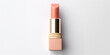 An peach fuzz color lipstick in a beige case on a white background. Make up a product show off. Copy space.