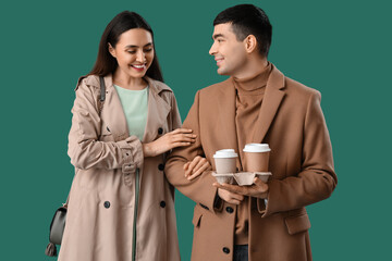 Canvas Print - Lovely young couple with cups of coffee on green background