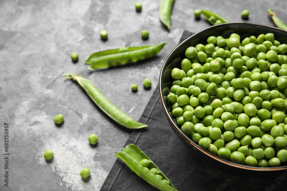 Bowl with fresh green peas on grey background