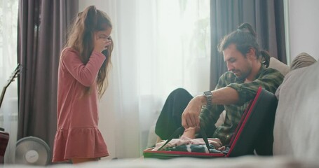 a little brunette girl in a pink dress and her father, a brunette man in a green checkered shirt, pu
