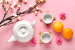 © Pixel-Shot - Teapot with cups, mandarins and sakura on pink background. Japanese New Year celebration