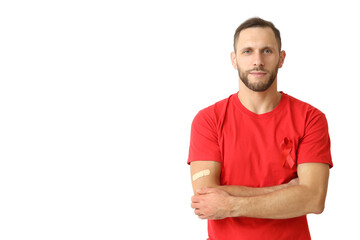 Wall Mural - Young man with red ribbon and crossed arms on white background. AID awareness concept