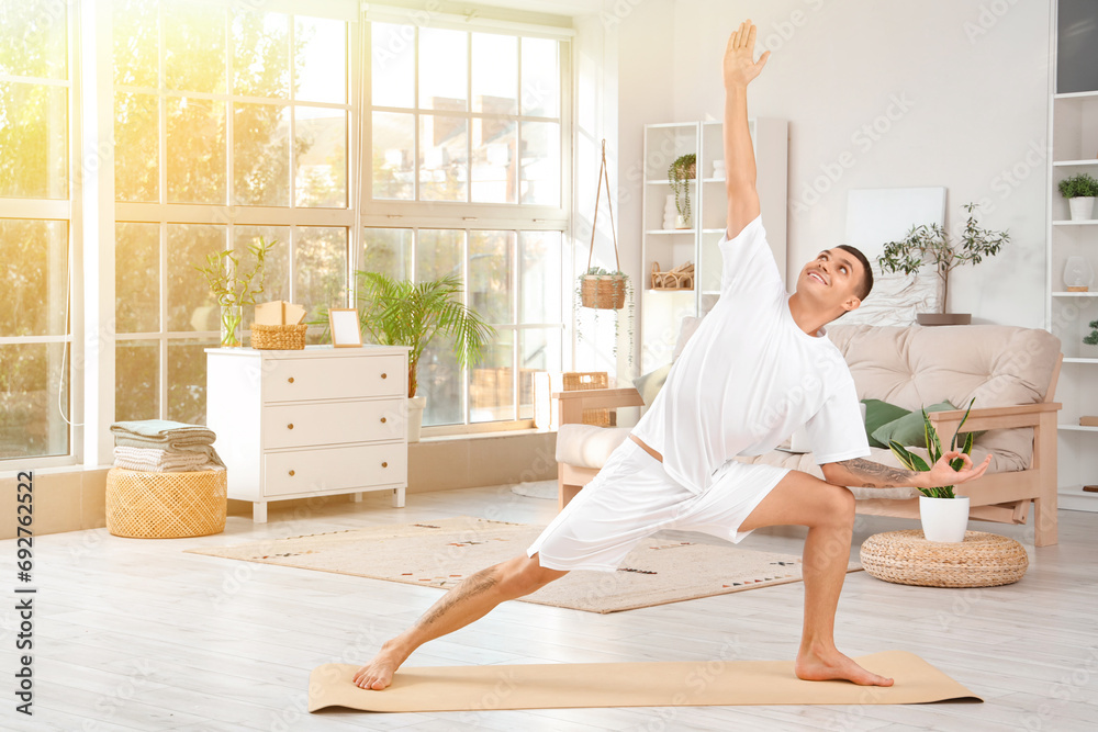 Young man doing yoga on mat at home
