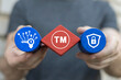 Man holding multi-colored blocks with icon sees trademark sign: TM. Trademark ( TM ) copyright or patent business industry technology web concept. Trade mark protection.