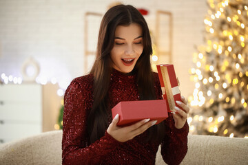 Poster - Surprised young woman with gift at home on Christmas eve