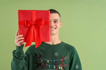 Sticker - Teenage boy with Christmas gift box on green background