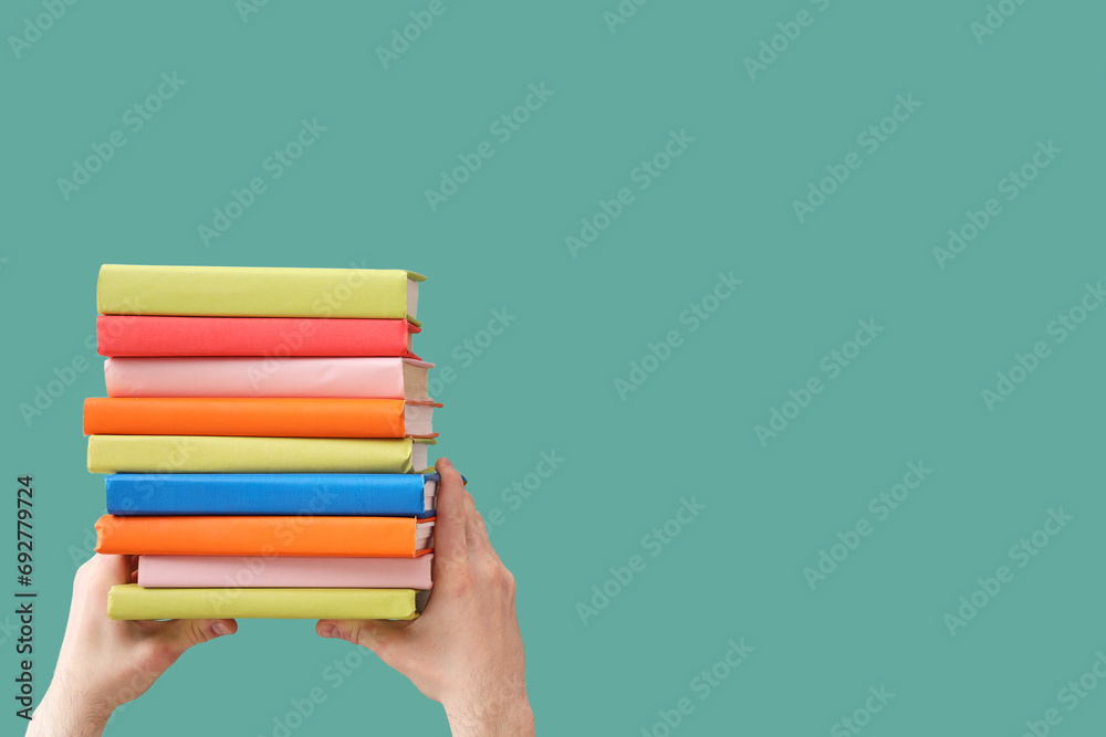 Hands holding books on green background