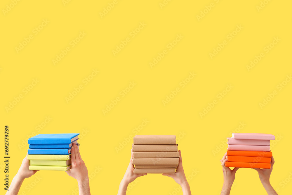 Hands holding books on yellow background