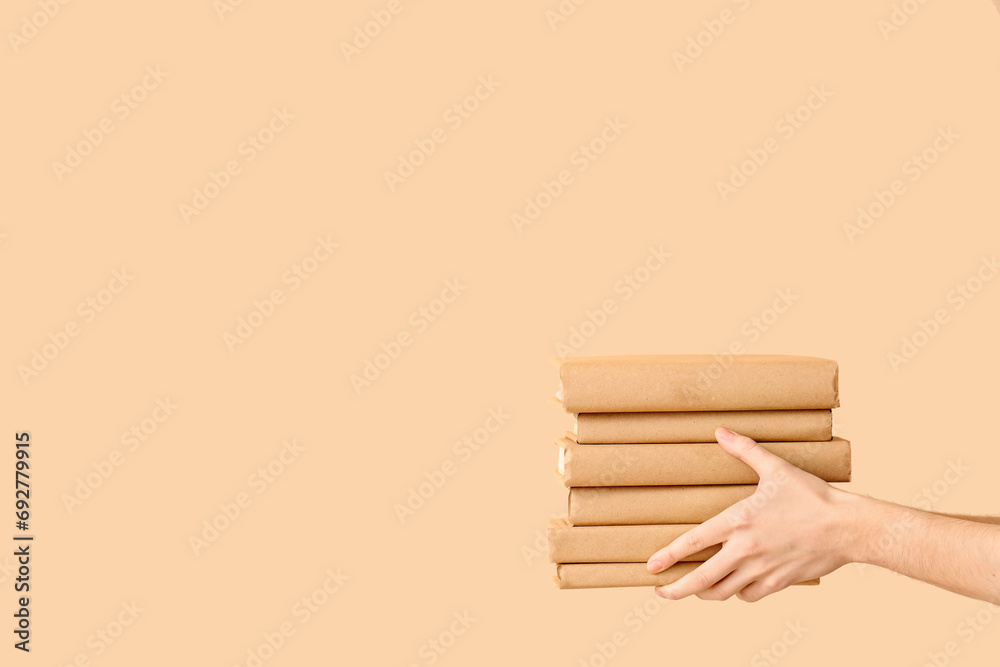 Hands holding stack of books on beige background
