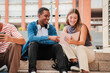 © Jose Calsina - Two multiracial teenage studens learning together at university campus. African american schoolboy talking with a school girl about the homeworks. Young friends studying at highschool stairs. High