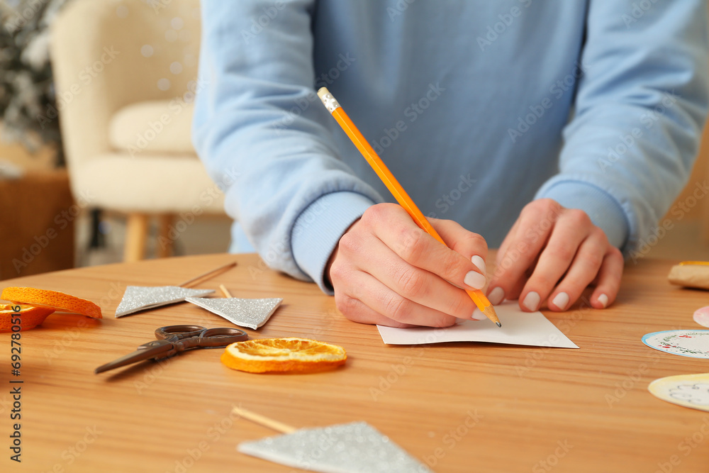 Woman making Christmas card at wooden table