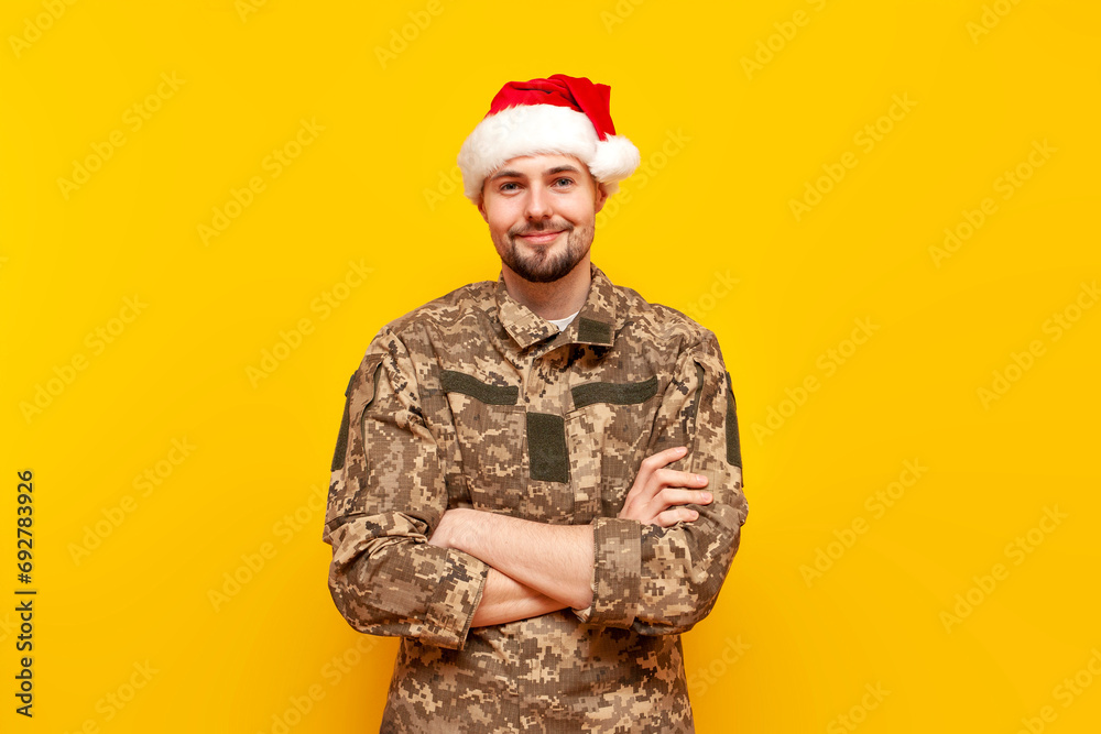 young ukrainian soldier in pixelated uniform and santa claus hat stands ...