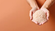 Hand holding organic rice grain isolated on pastel background