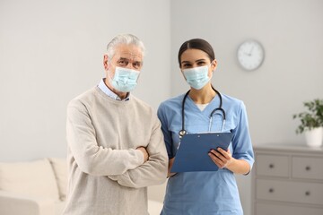 Poster - Nurse and elderly patient wearing protective masks in hospital