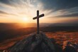 A rustic wooden cross sitting on top of a remote hill with a sunset or sunrise in the background.