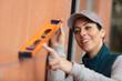 female builder using spirit level against exterior wall
