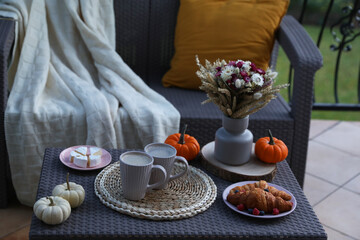 Wall Mural - Rattan table with cups of drink, croissants, cheese and autumn decor on terrace