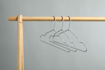 Poster - Empty clothes hangers on wooden rack against grey background