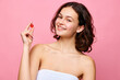 Nutrition ampule. Pretty in young brunette girl with curly hair standing in shower towel against pink background. Concept of natural female beauty, skin care, cosmetology and cosmetics