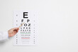 Ophthalmologist pointing at vision test chart on white background, closeup. Space for text