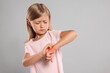 © New Africa - Suffering from allergy. Little girl scratching her hand on light gray background, space for text