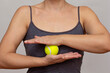 Cropped woman body rolling tennis ball between hands doing exercises over grey background