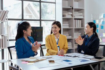 Wall Mural - Happy asian business women colleagues applauding in meeting at workplace