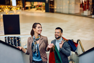 Wall Mural - Young smiling couple on escalator in shopping mall.