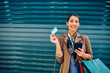Happy woman using credit card and mobile phone while shopping and looking at camera.