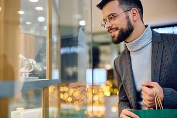 Wall Mural - Young man looking at store window while shopping at  mall.