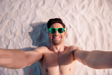 Poster - Top view photo of cheerful positive guy swimwear lying sand recording video vlog outside ocean beach