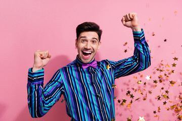 Sticker - Photo of delighted positive guy raise fists shout yes flying star shape confetti isolated on pink color background