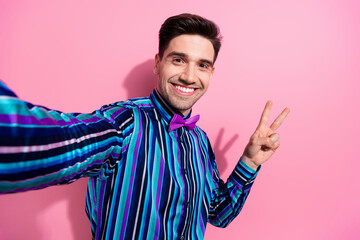 Sticker - Photo of cheerful nice young man toothy smile make selfie demonstrate v-sign isolated on pink color background