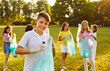 © Studio Romantic - Portrait of preteen boy collecting plastic trash during summer cleanup in park. Child puts plastic bottle in garbage bag while standing against background of his peers who are cleaning on green lawn.