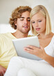 © Tabitha Rose/peopleimages.com - Research, tablet and young couple on sofa browse on social media or internet at apartment. Happy, digital technology and man and woman from Australia relax and scroll on website in lounge at home.