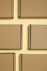 Wall Mural - Many closed cardboard boxes on pale yellow background, flat lay