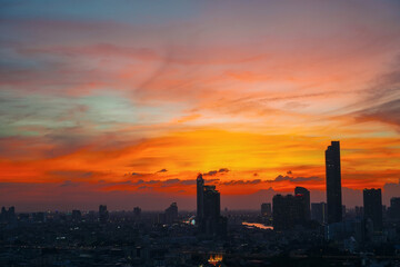 Wall Mural - Sunset over modern office buildings in business district. Skyline view of cityscape with sunlight and flare in warm light color tone.
