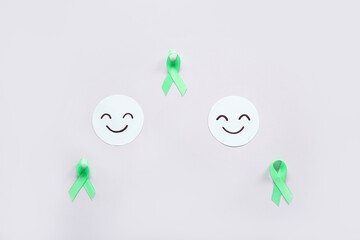 Wall Mural - Happy smile faces with green awareness ribbons on grey background. Mental Health Day