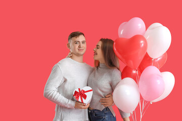 Lovely couple with gift box and heart-shaped balloons on red background. Valentine's Day celebration