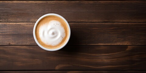 Foamy coffee on wooden table, seen from above.