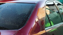 An Elderly Man Wiping A Car After Washing It. Close-up Of A Hand With A Rag Wiping Water Drops From The Roof Of A Red Car. Hand Washing A Car In His Yard