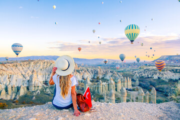 young female tourist with colorful hot air balloon flying over cappadocia landscape- travel, vacatio