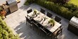 Stylish outdoor kitchen with gas barbecue and dining table set for guests, formal place settings and flowers on paved patio, seen from high angle.