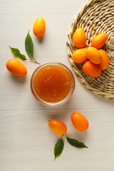 Sticker - Kumkvat and jar of jam on light wooden background, top view