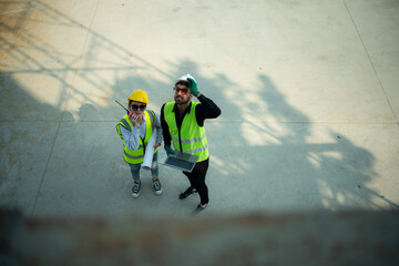  Overhead view on a building site, an engineer and architect are discussing on a laptop.